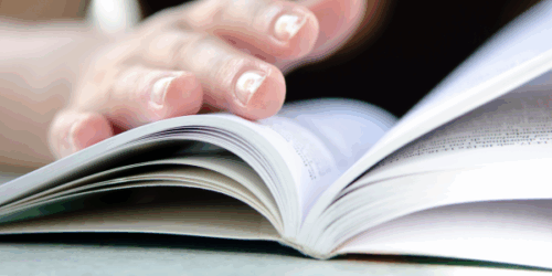 Un livre ouvert avec une main qui lit ce livre (le guide utilisateur Linphone).